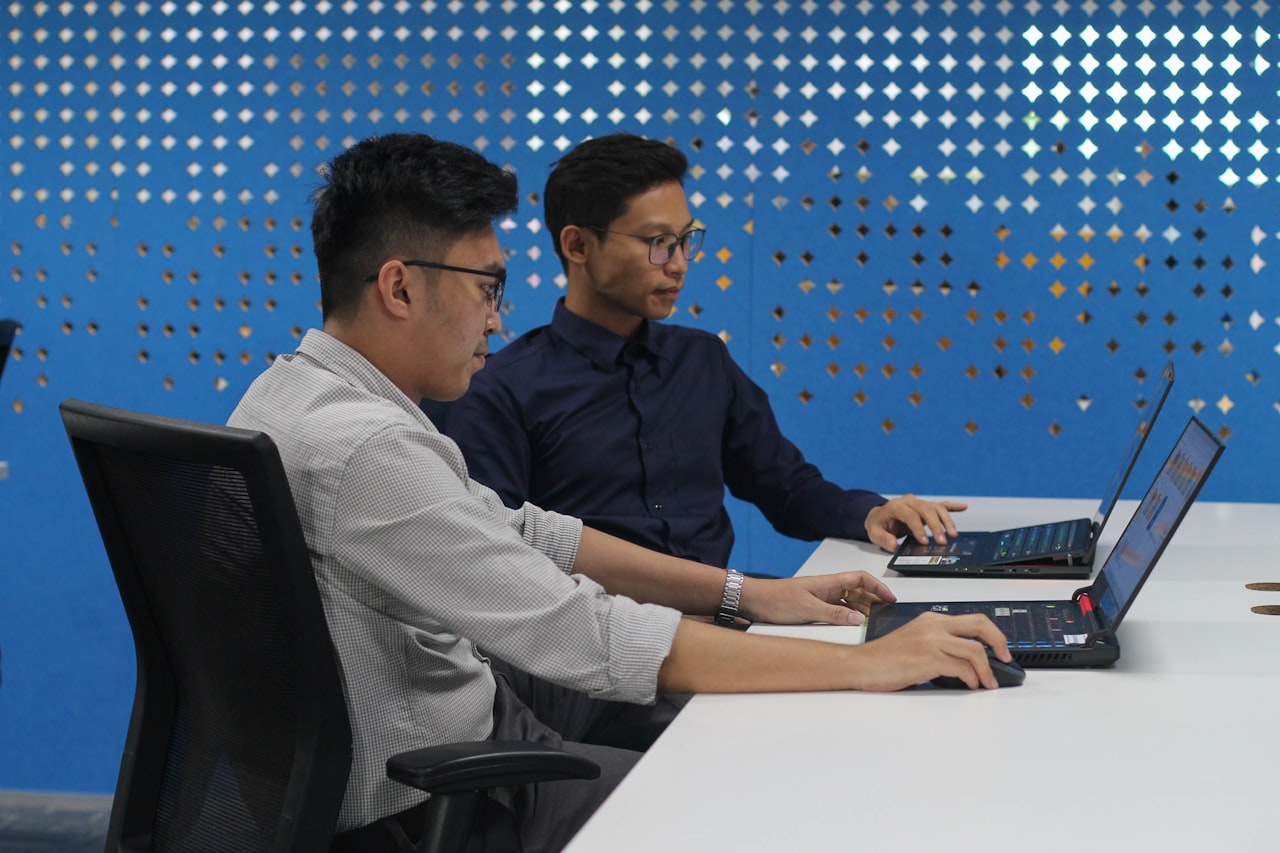 Dua pekerja muda di komputer riba dalam pejabat moden, mewakili tenaga kerja anotasi data AI Asia Tenggara yang semakin berkembang