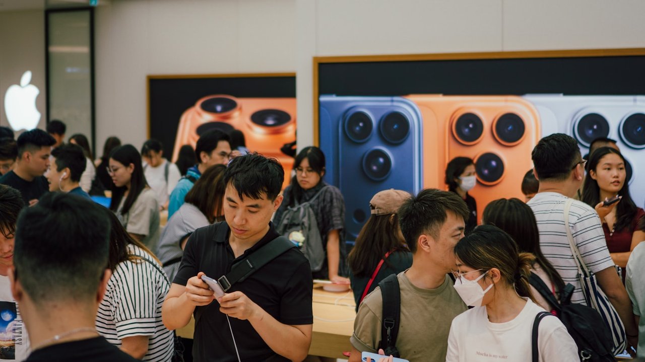 Orang ramai memenuhi kedai Apple pada hari pelancaran iPhone dengan paparan kamera iPhone Pro di dinding