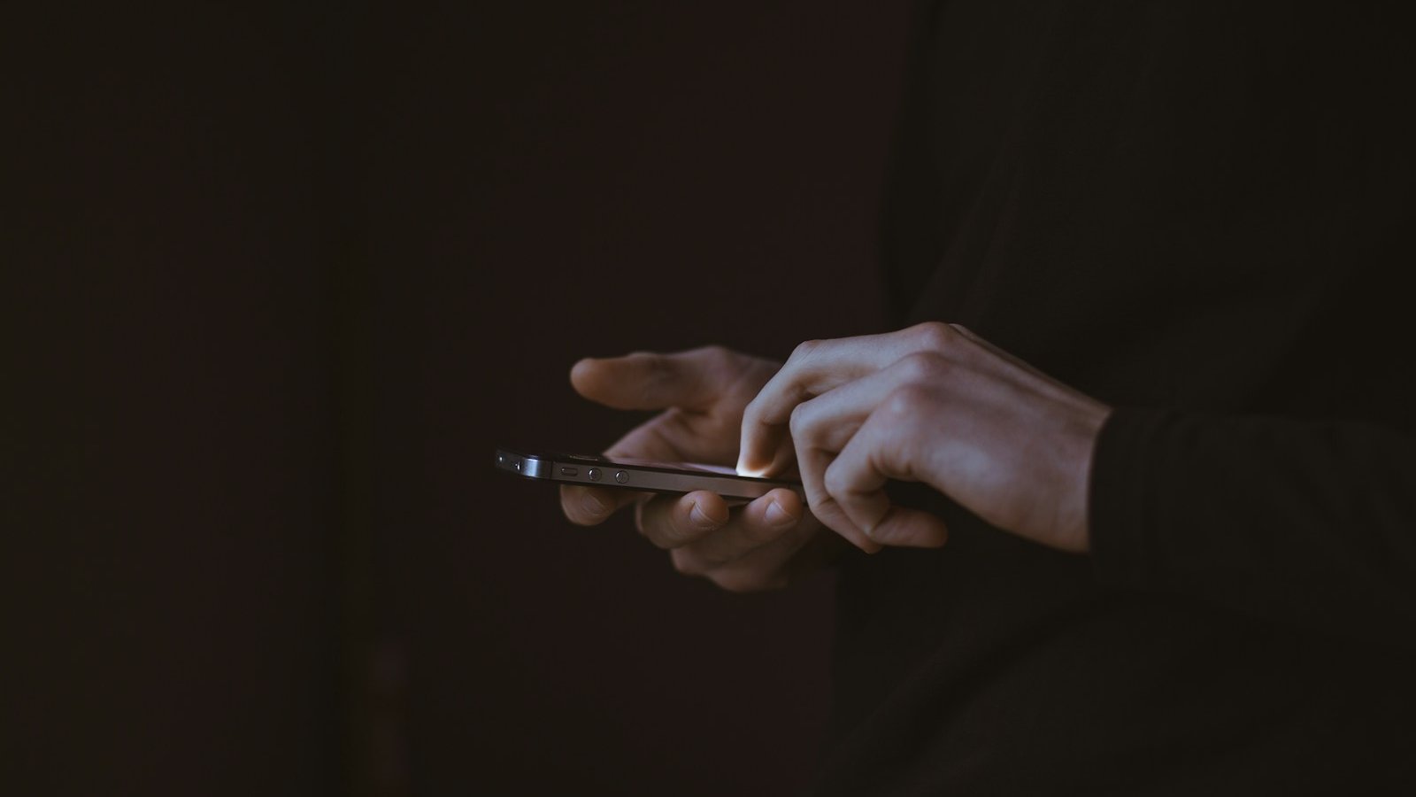 Seseorang mengetuk skrin telefon pintar dalam cahaya malap