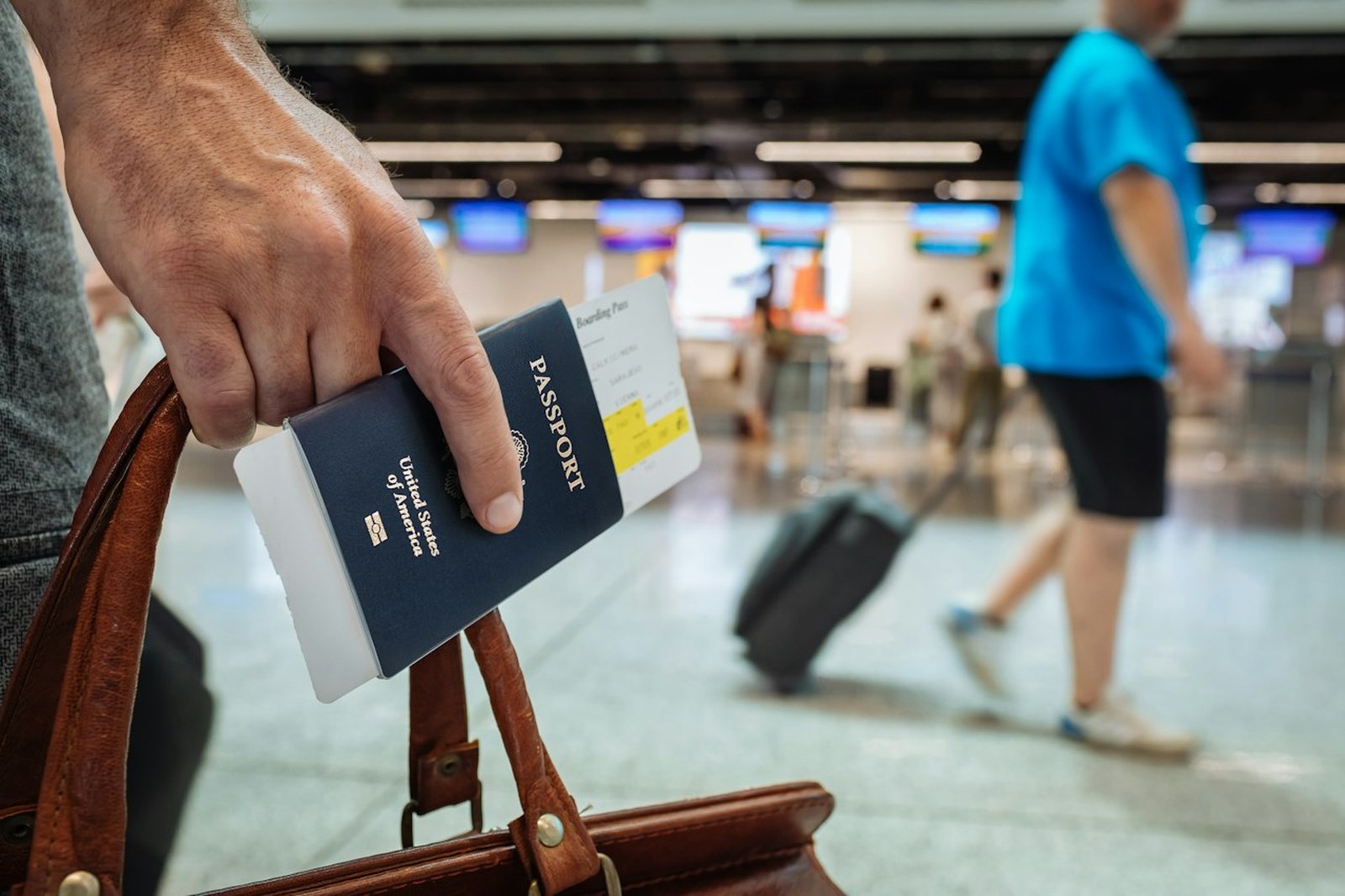 A traveller holds a passport and boarding pass while walking through an airport terminal