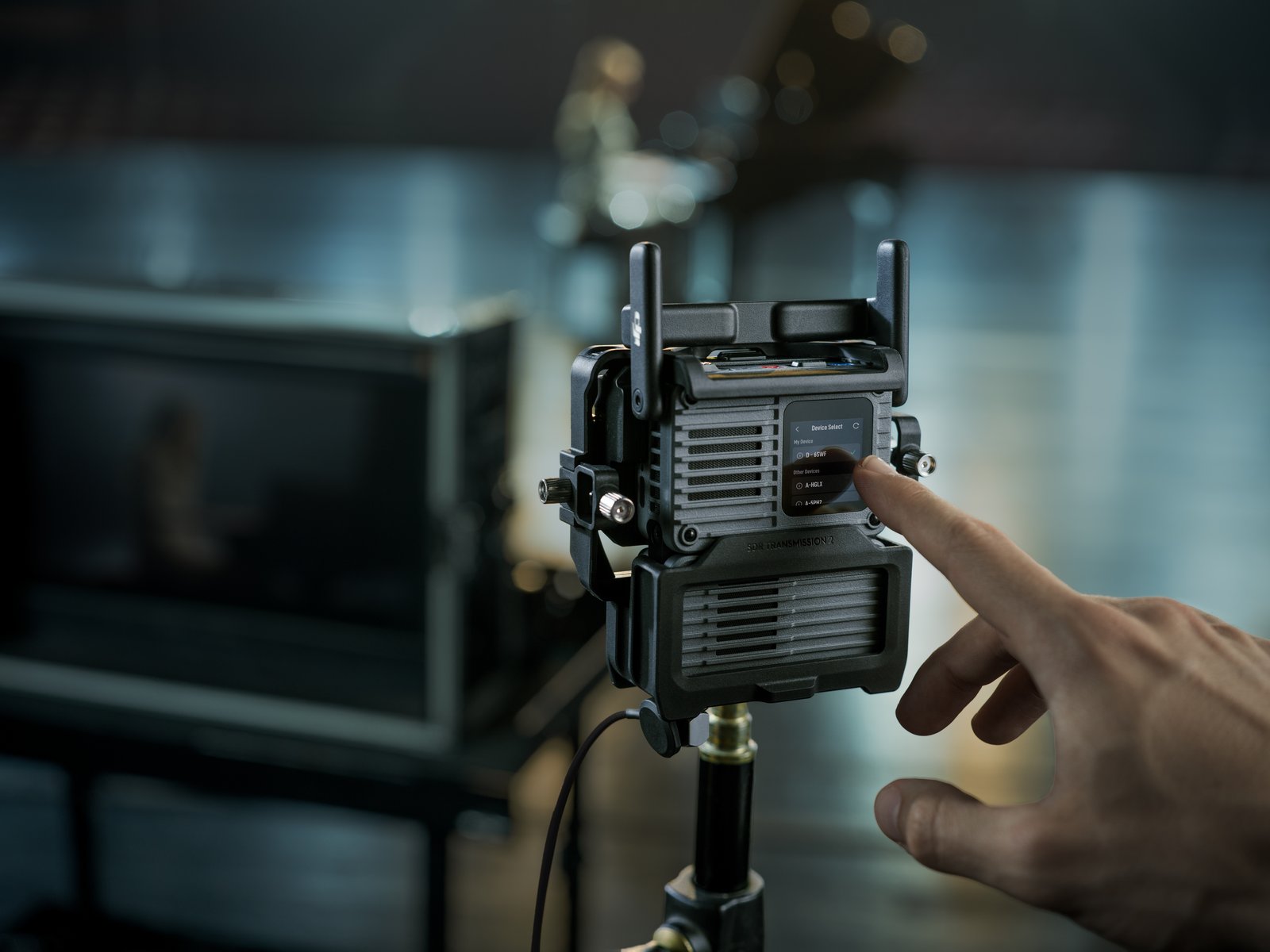 Tangan melaraskan tetapan pada transceiver DJI SDR Transmission 2 di set filem