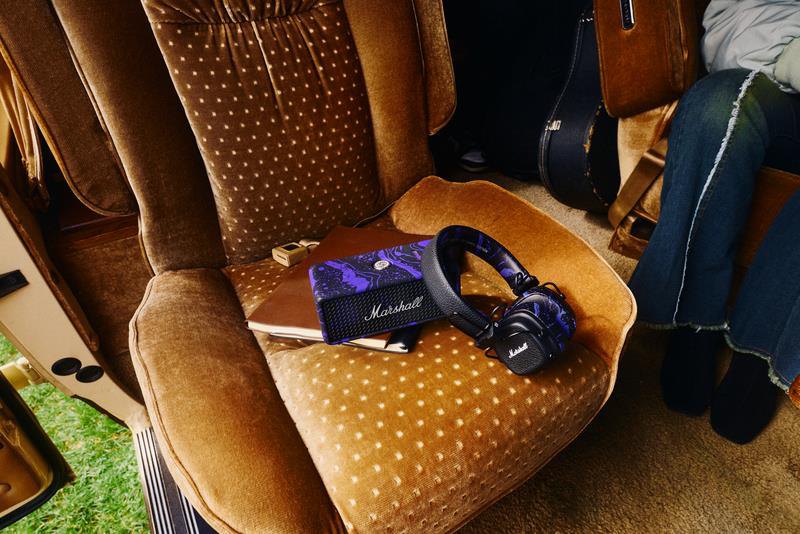 Marshall Hendrix Edition Major V headphones and Emberton III speaker in a purple oil-on-water finish on a velvet chair