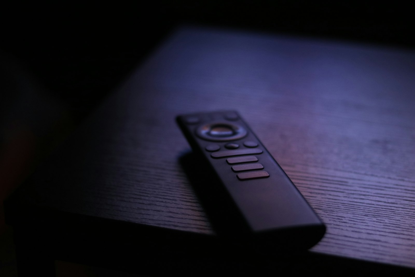 A smart TV remote control on a dark table