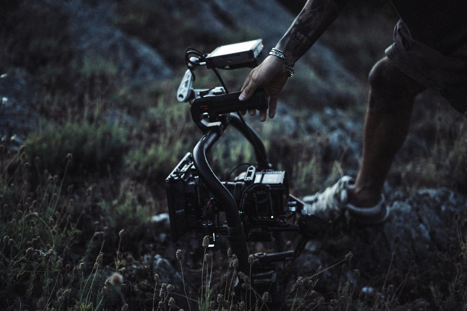 A videographer carries a camera on a handheld gimbal stabiliser rig outdoors