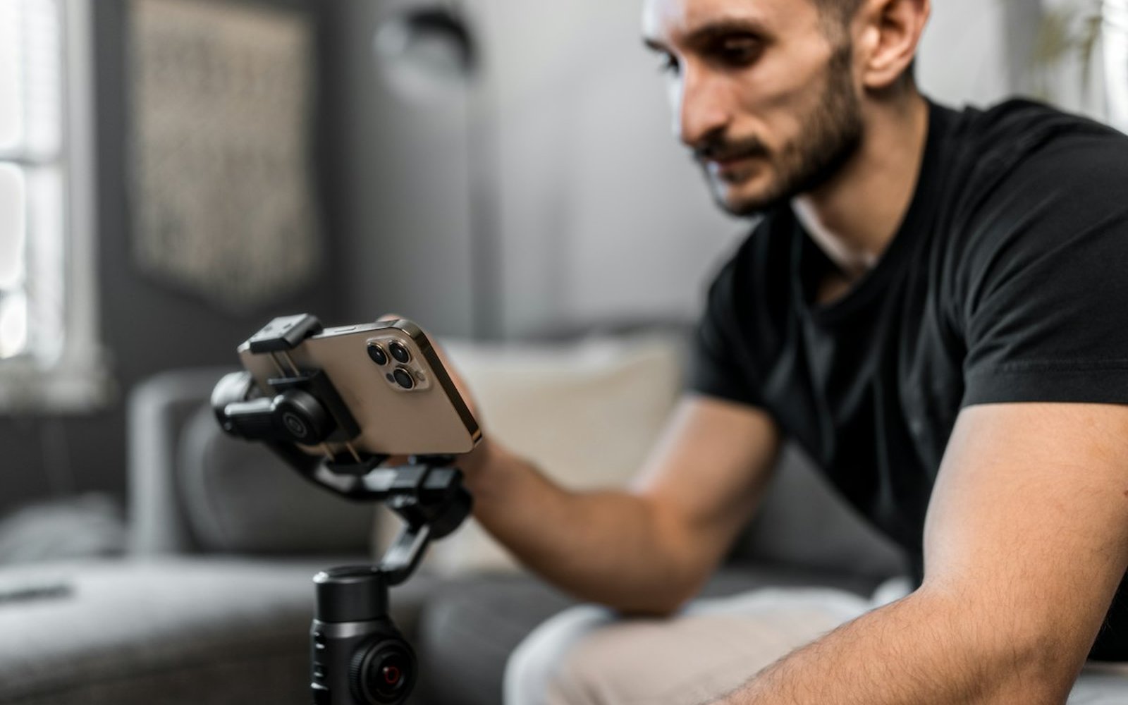A creator adjusts a smartphone mounted on a motorised gimbal while seated indoors