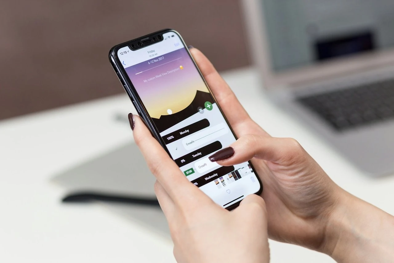 Seseorang memegang iPhone dan mengetuk aplikasi pada skrin