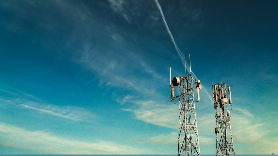 Two 5G telecommunications towers against a blue sky