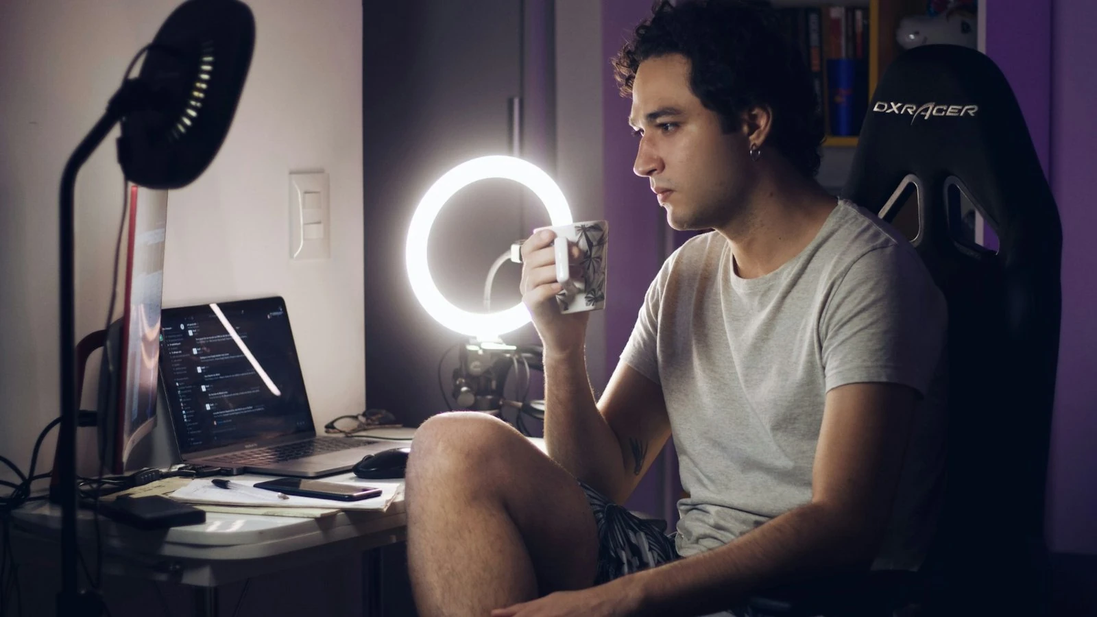 A content creator at a desk with a ring light, laptop and phone