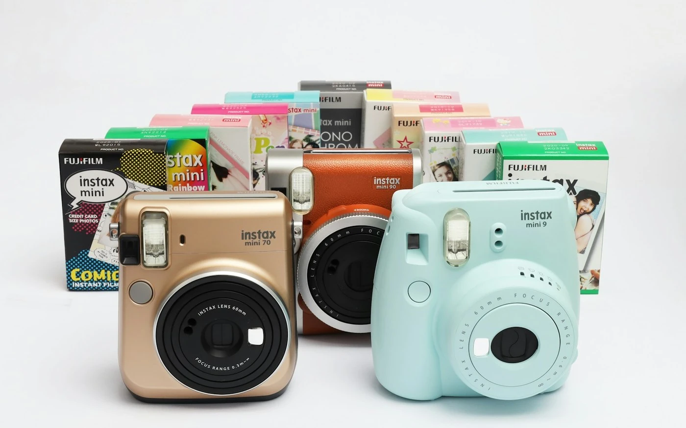 A row of Fujifilm Instax instant cameras with boxes of Instax Mini film