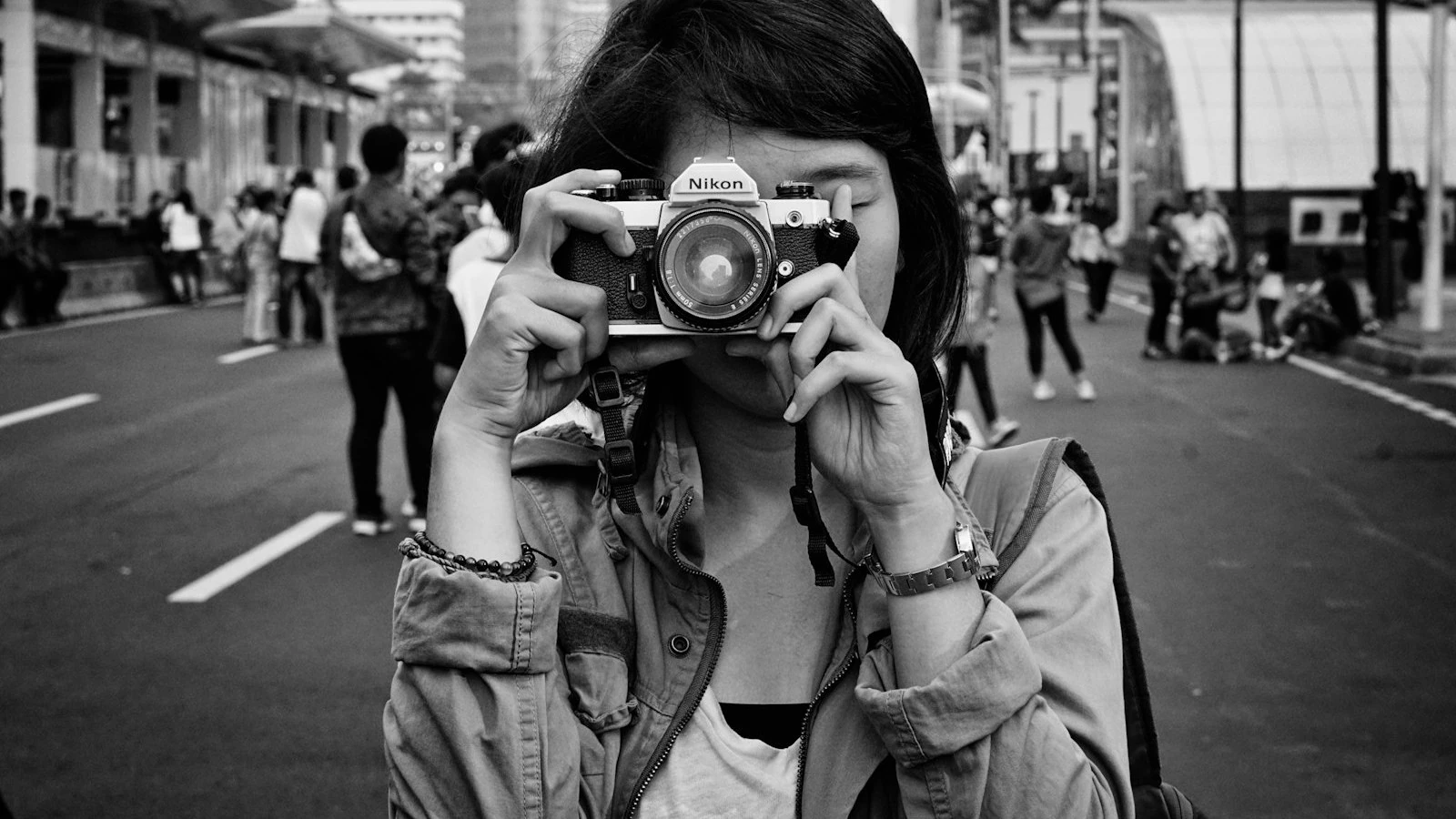 Seorang jurugambar muda merakam dengan kamera SLR filem di jalan bandar