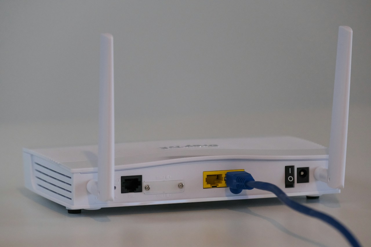 Sebuah router Wi-Fi jalur lebar rumah dengan kabel ethernet biru dipasang di belakang