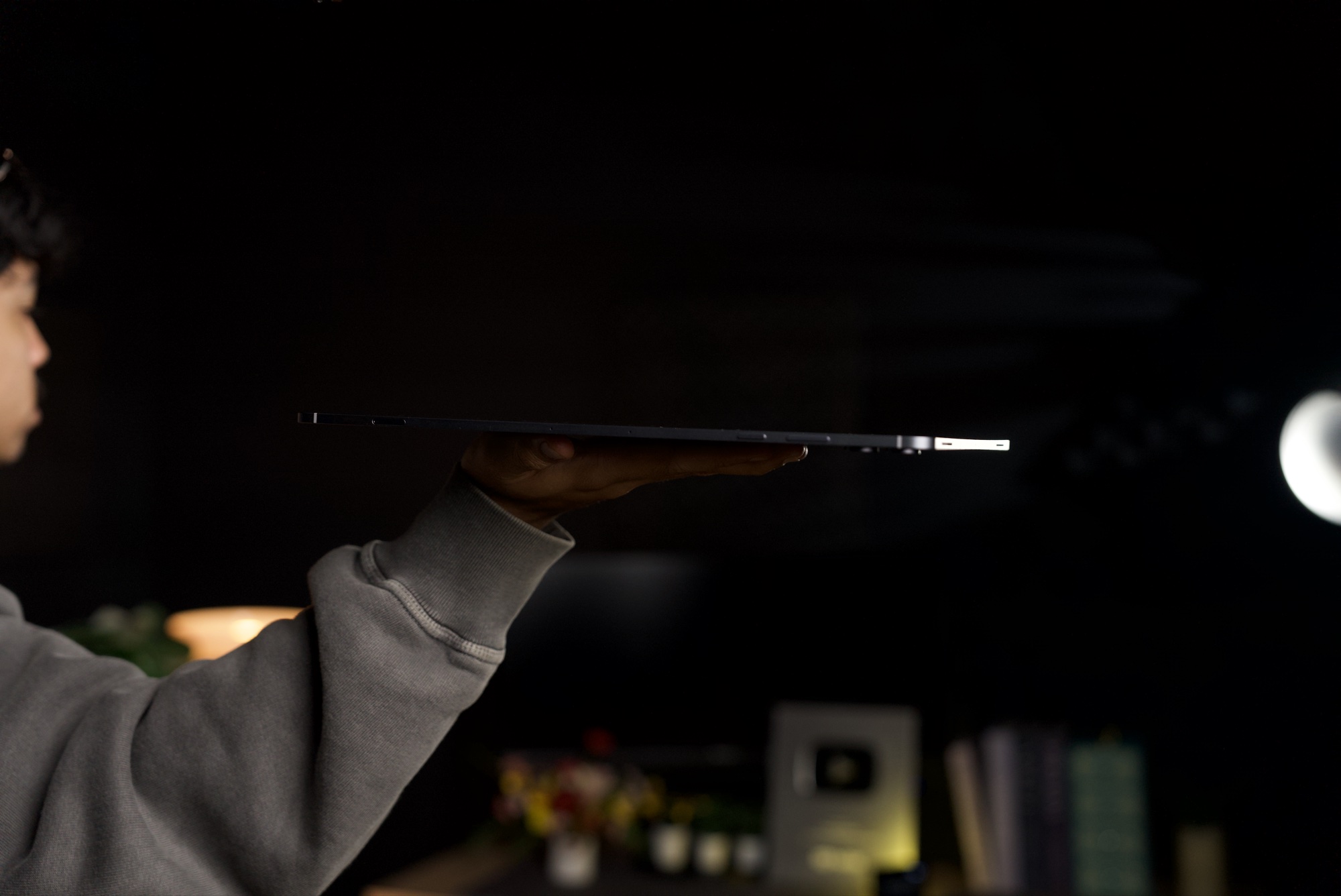 The Galaxy Tab S12 Ultra seen from the side, held flat on one hand to show how thin it is