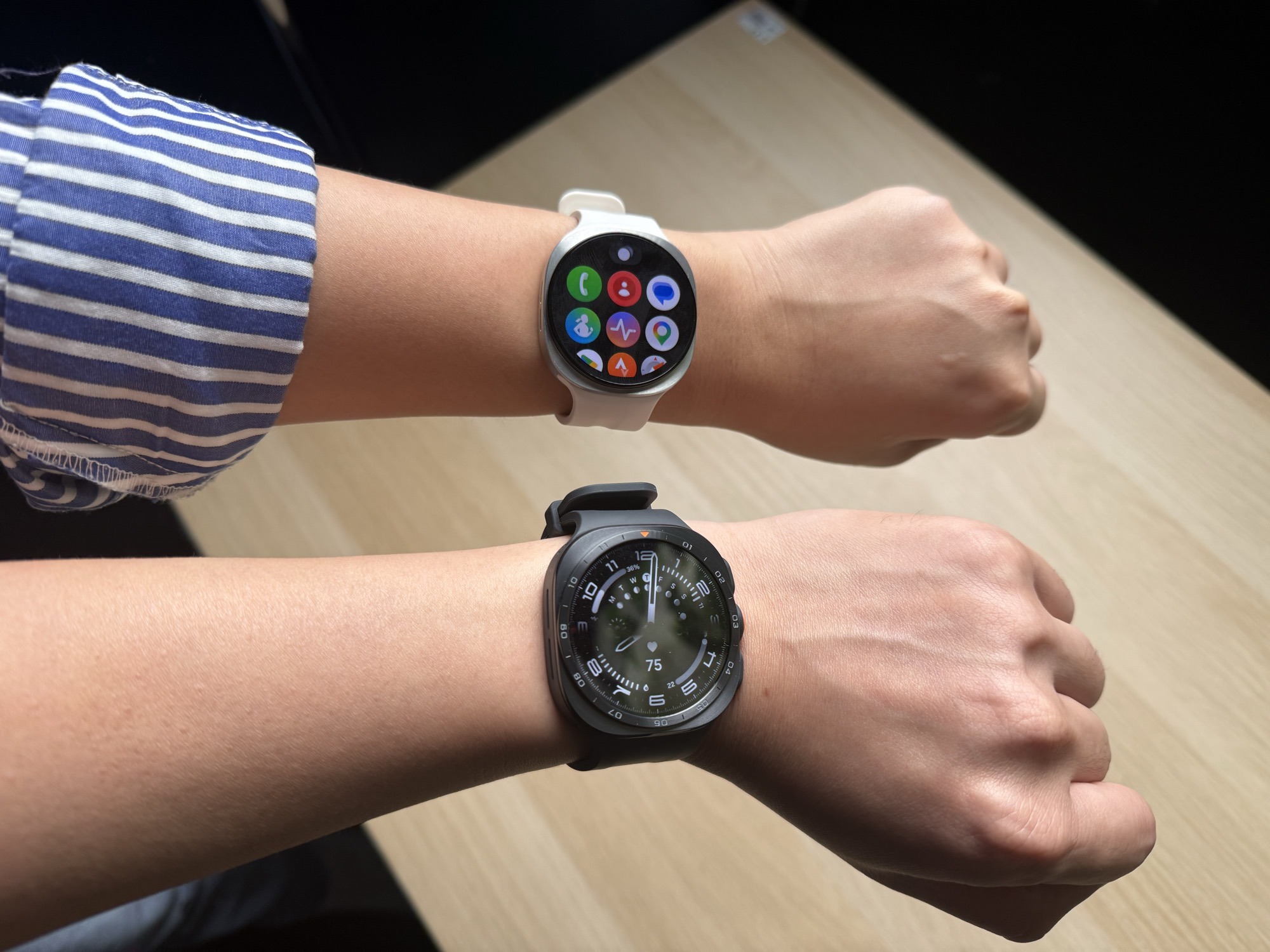 The Galaxy Watch9 in white beside the larger Watch Ultra 2, worn on two wrists