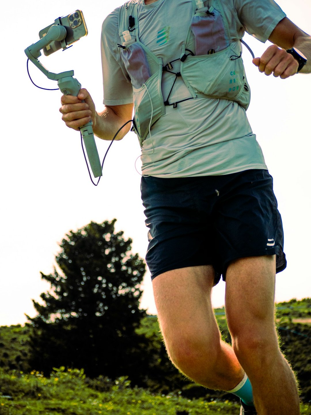 A runner films himself outdoors using a smartphone mounted on a handheld gimbal