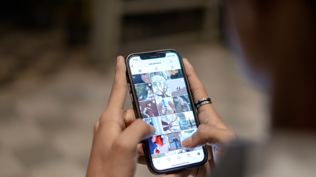 A hand holding a smartphone scrolling a social media app feed