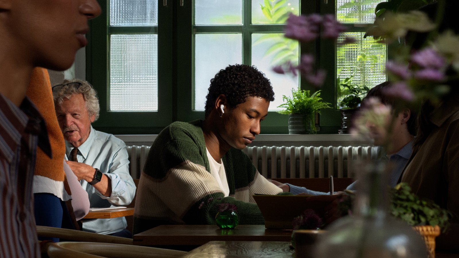 AirPods 5 worn in a cafe, Apple press image