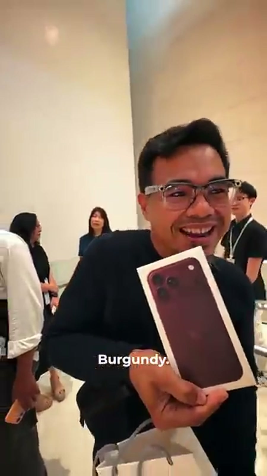 A buyer at Apple TRX holding his new iPhone 18 Pro in Burgundy