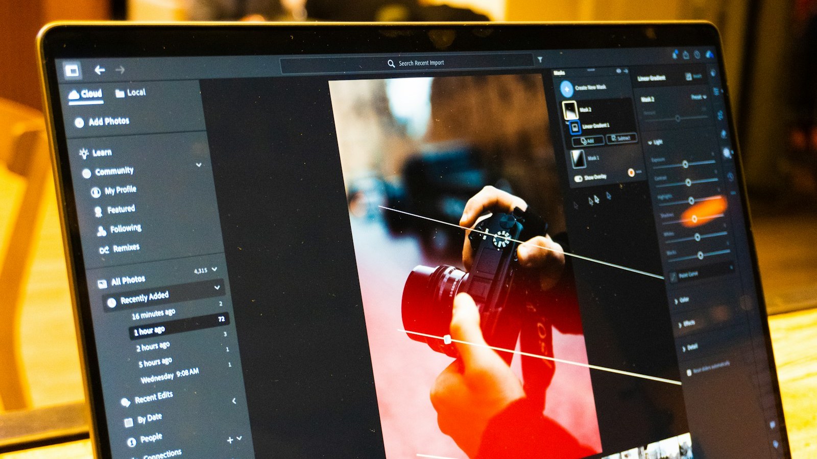 A laptop running Adobe Lightroom edits a photo of a photographer holding a camera