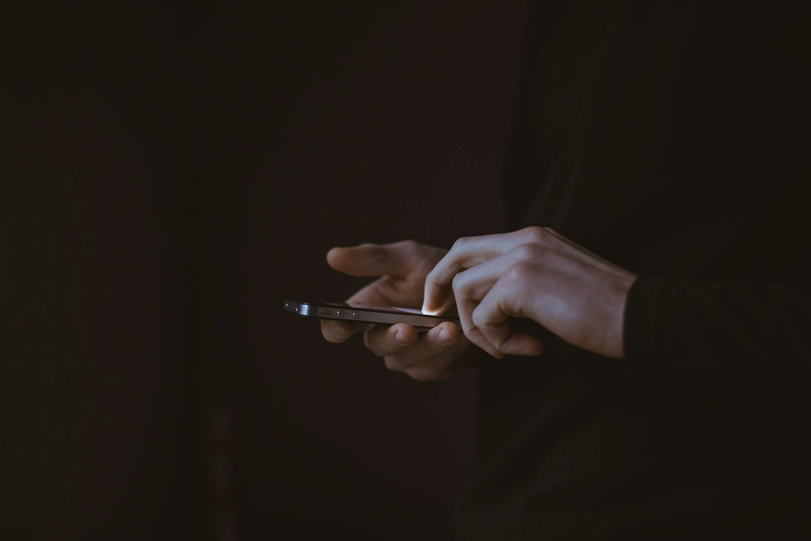 A person tapping on a smartphone in a dark room