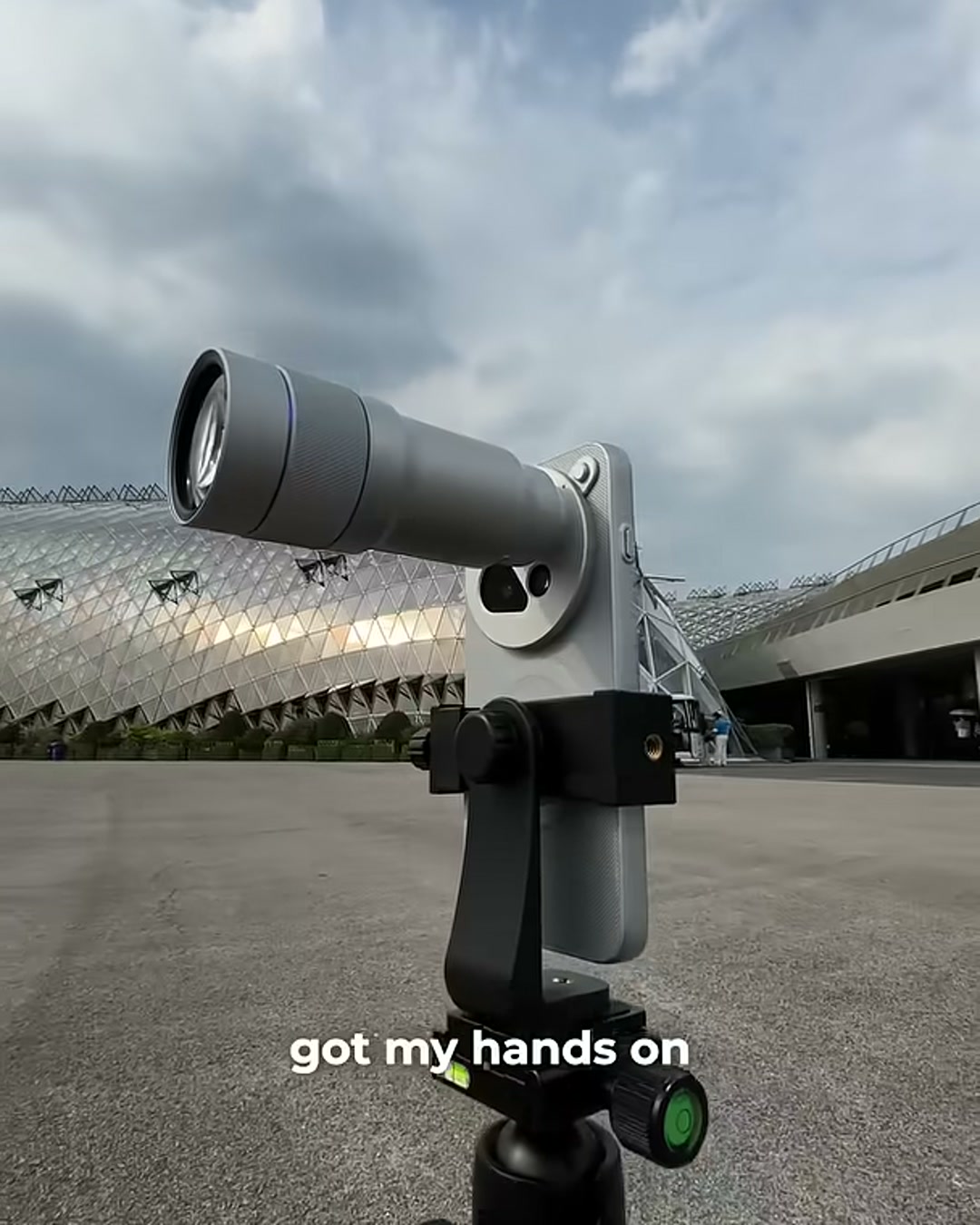 The vivo X500 Pro Max with its clip-on lens mounted on a tripod grip