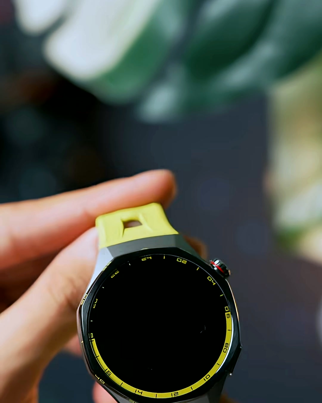 Holding the HUAWEI Watch GT 7 Pro with its screen off, showing the octagonal case and yellow silicone band