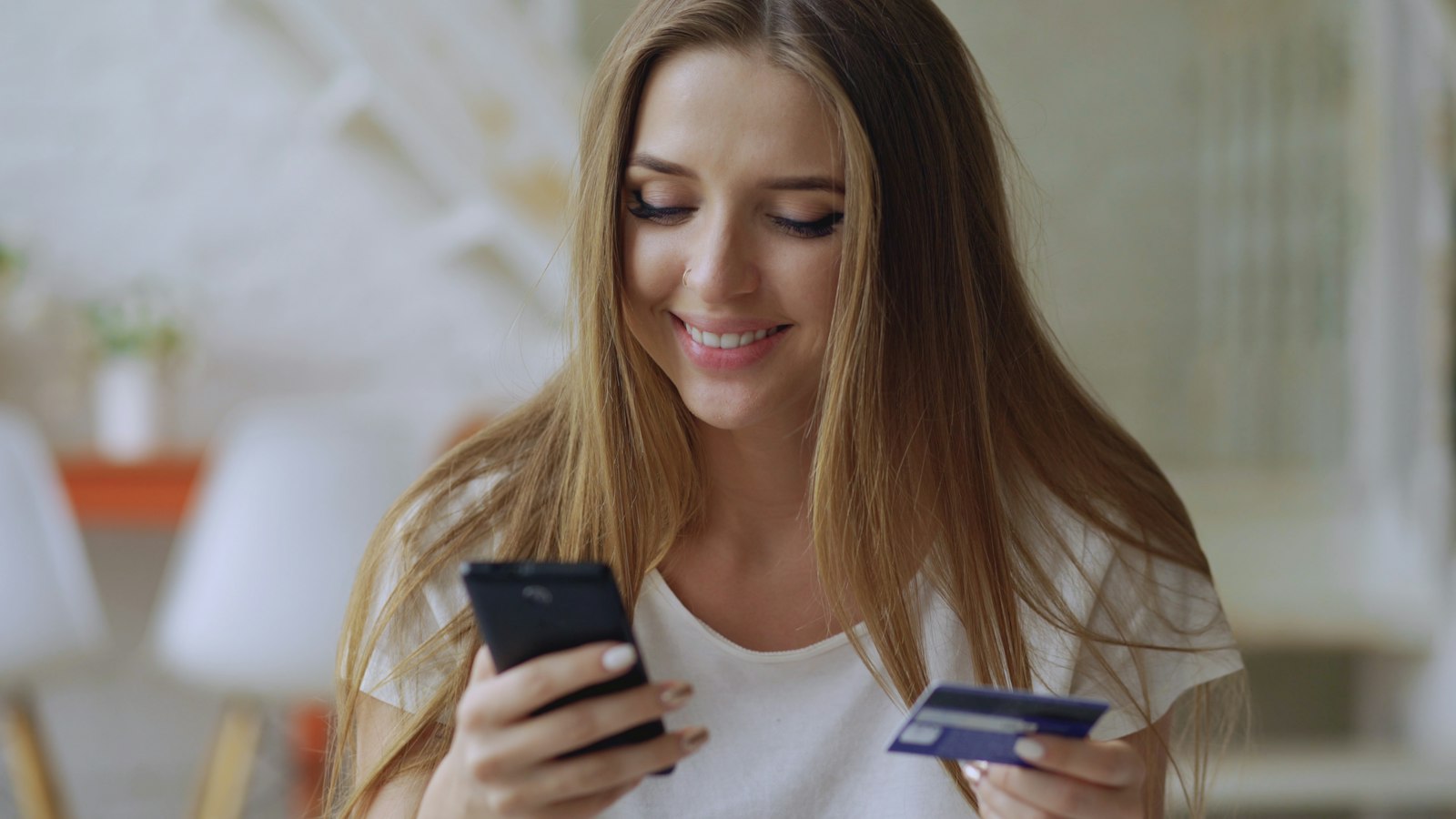 A shopper comparing a price on a phone while holding a bank card before the 10.10 sale