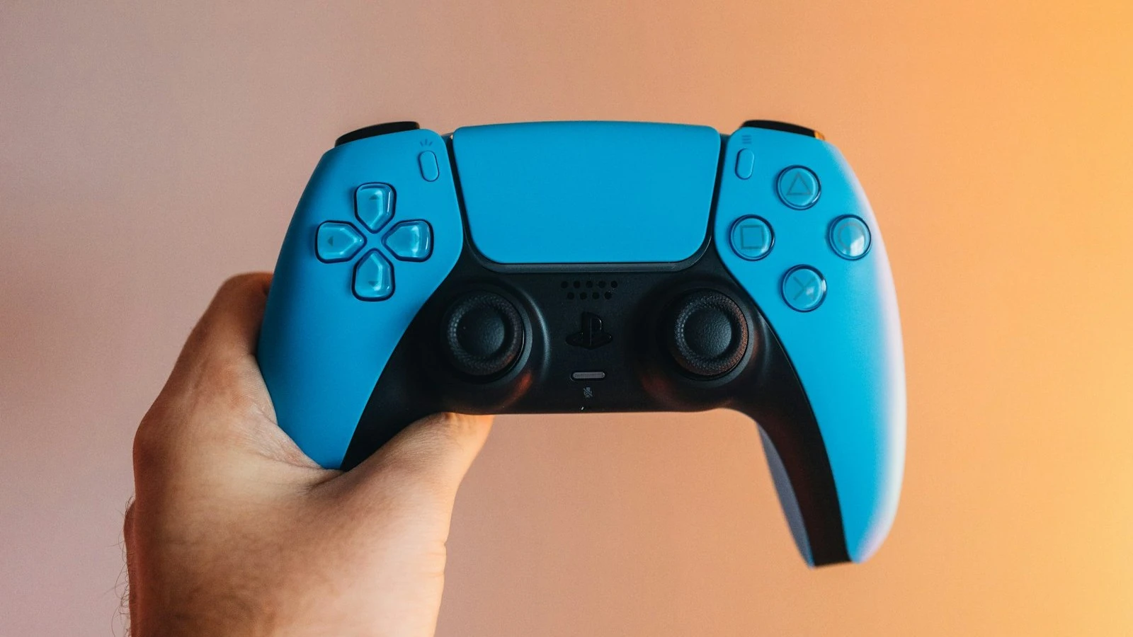 A blue PS5 DualSense controller held up in one hand