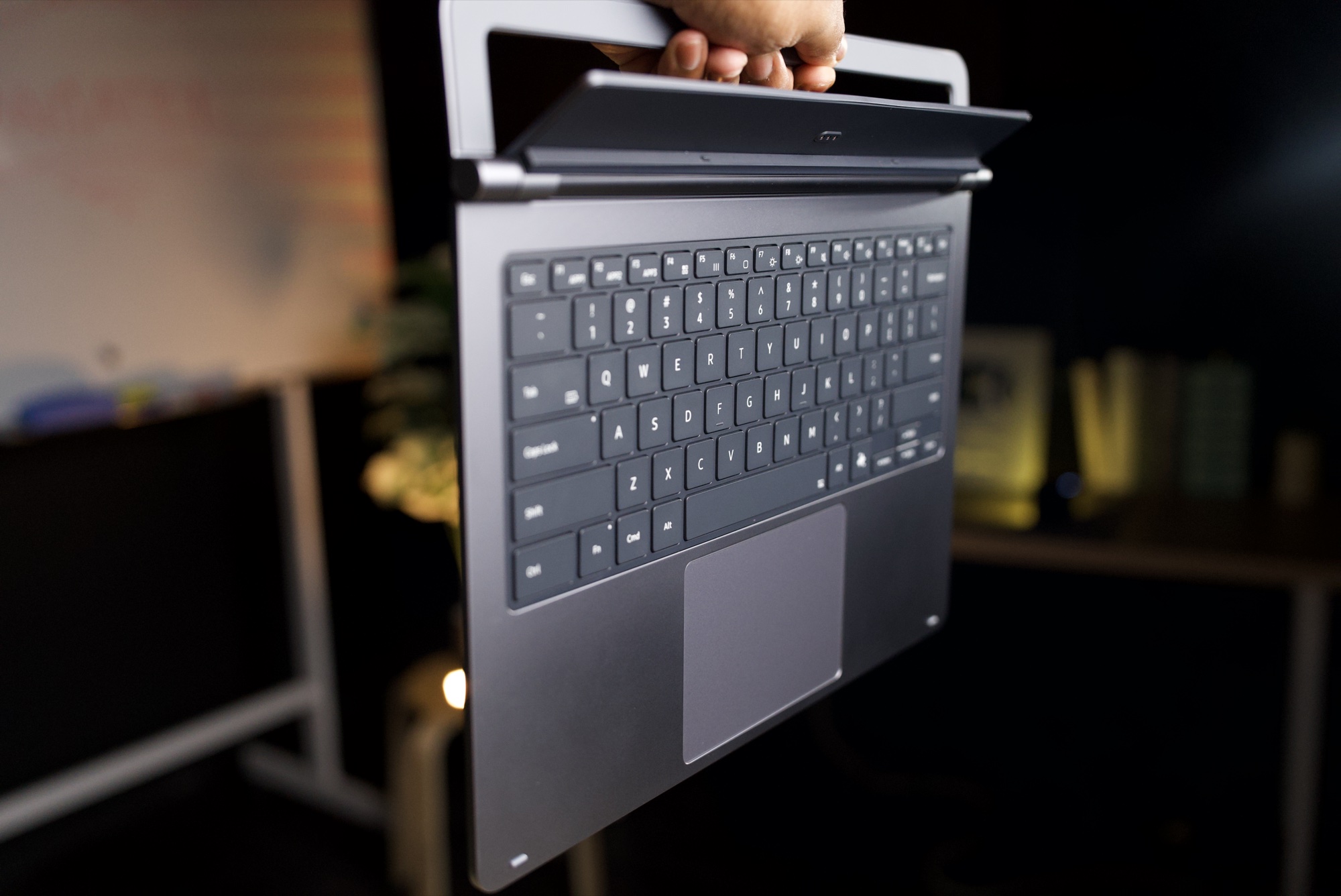 The Pro Keyboard held up by hand, showing its slim profile and the cradle at the back