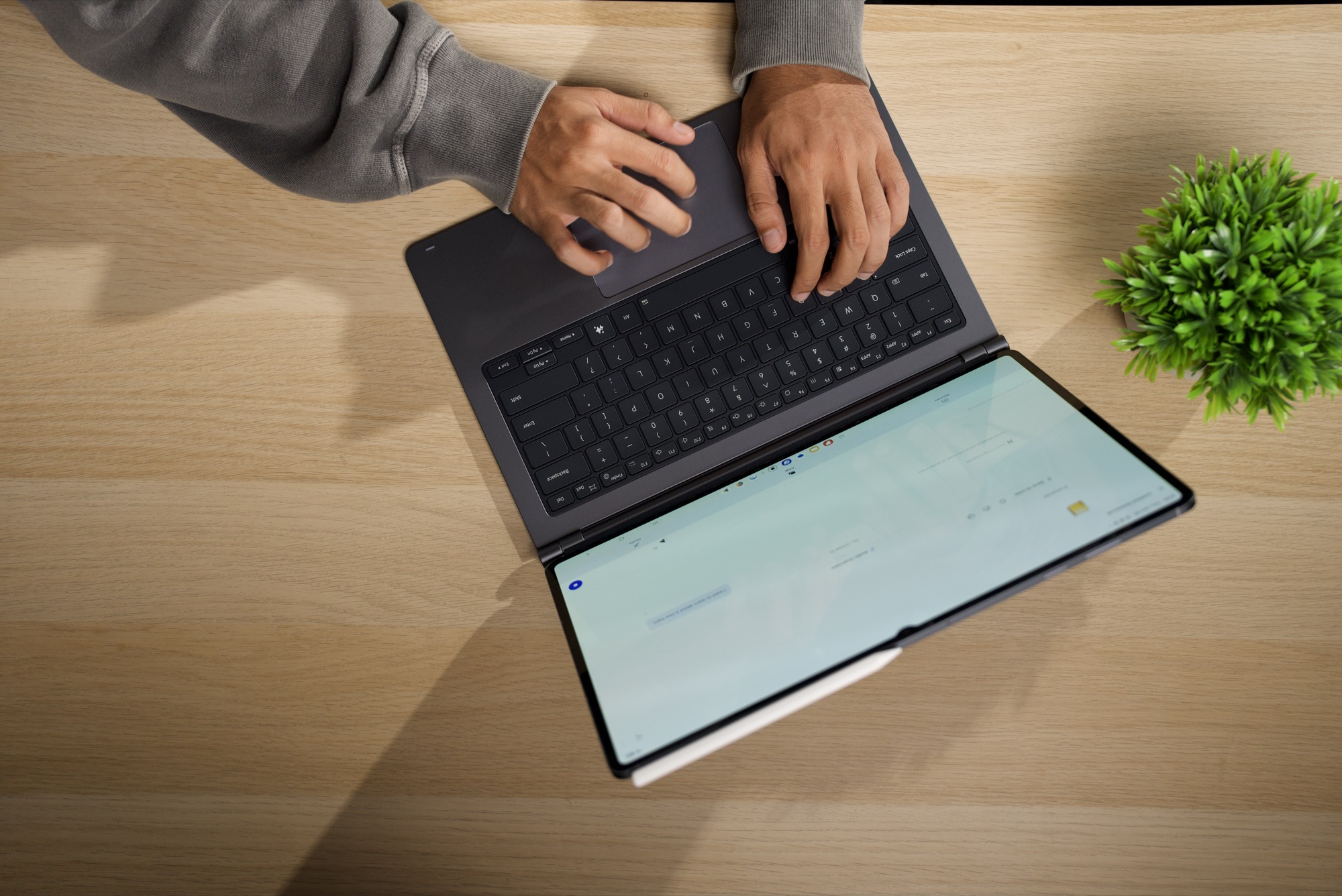 A top-down shot of hands on the Pro Keyboard's keys and trackpad, with the Galaxy Tab S12 Ultra in front