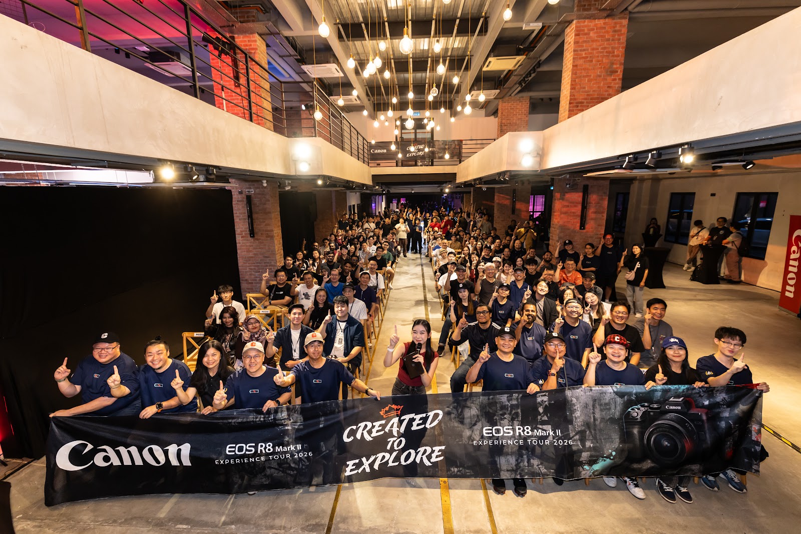 Attendees at the Canon EOS R8 Mark II Experience Tour launch in Kuala Lumpur holding the Created To Explore banner